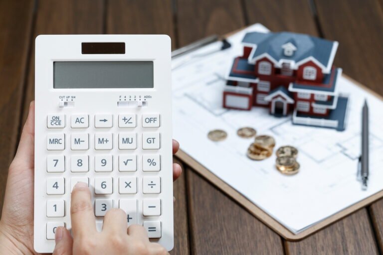 A female hand operating a calculator in front of a Villa house model